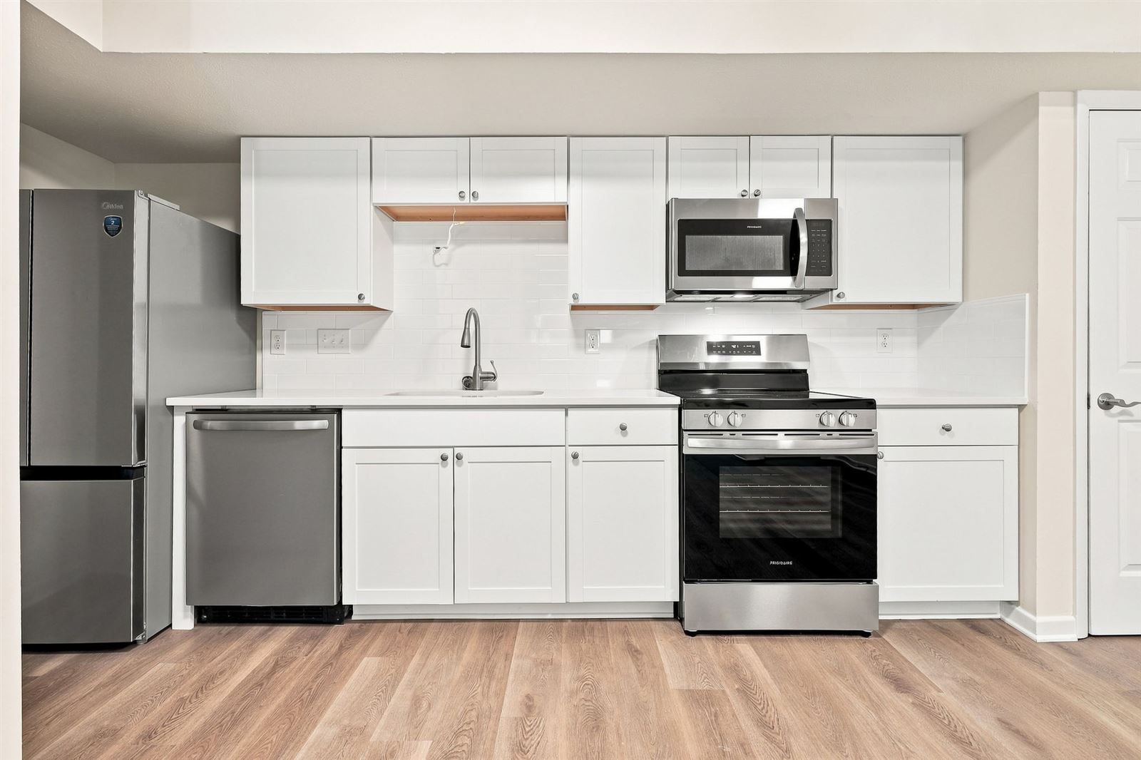 Kitchen with white shaker cabinets, quartz counters and stainless appliances